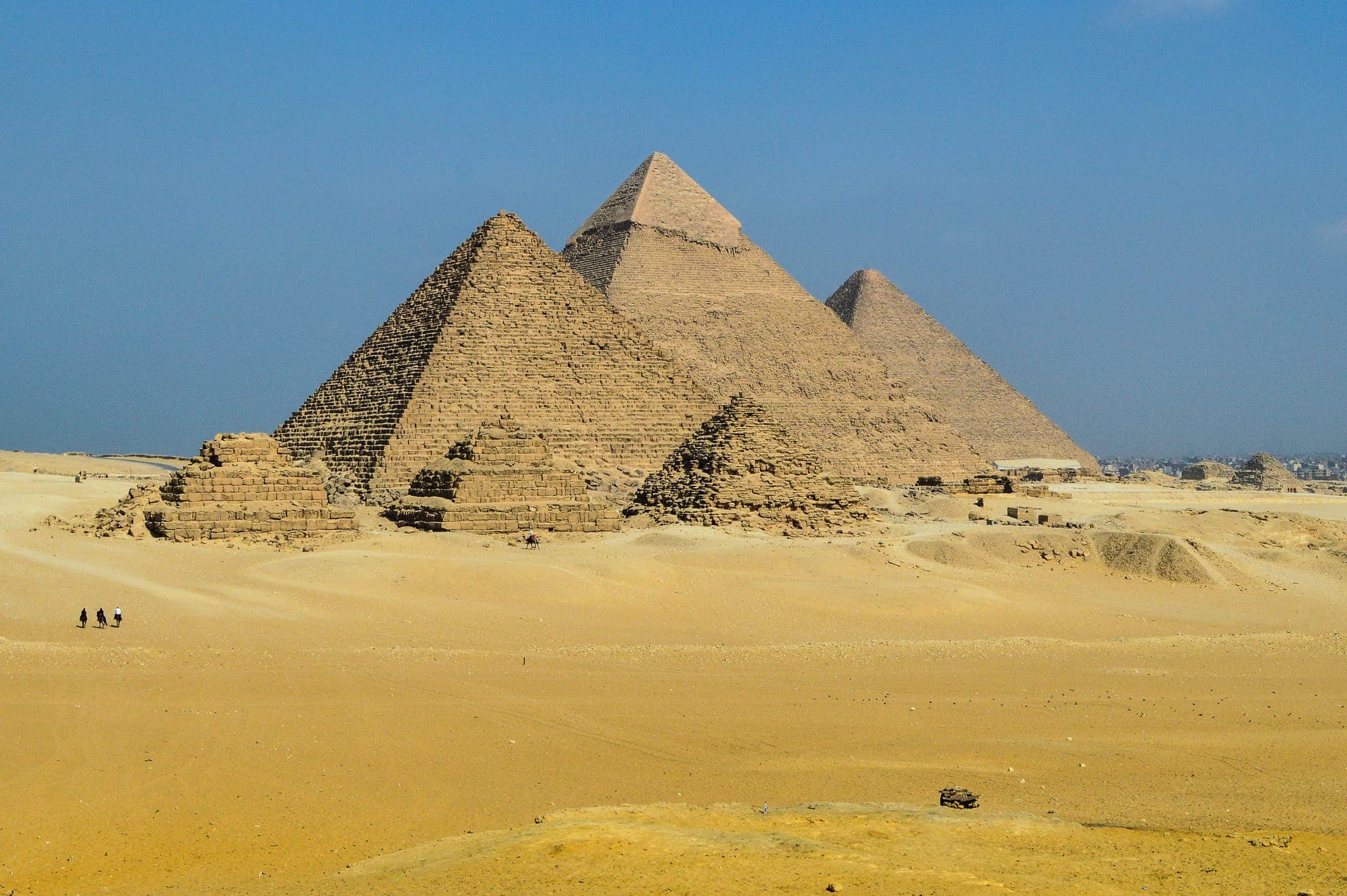 The pyramids of Giza standing in the desert under a clear sky