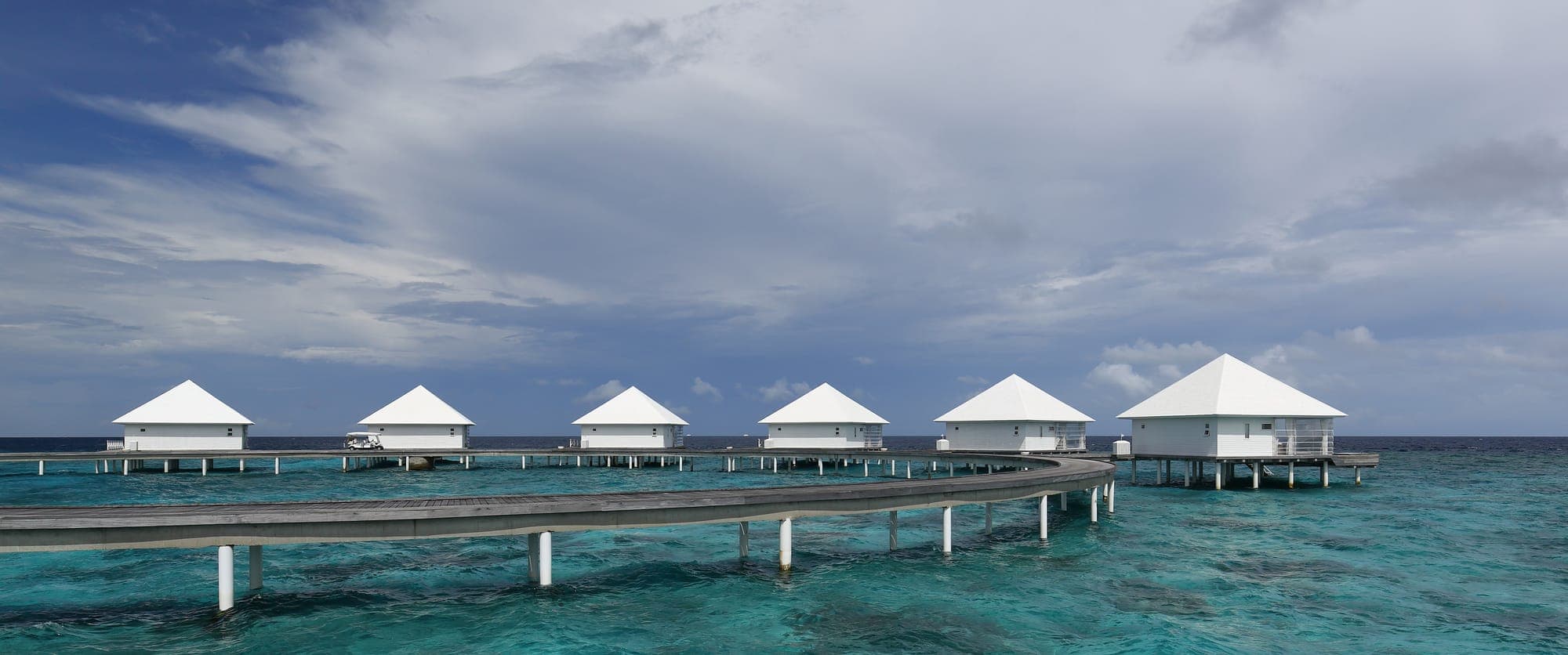 Overwater villas on stilts above a clear turquoise lagoon in the Maldives